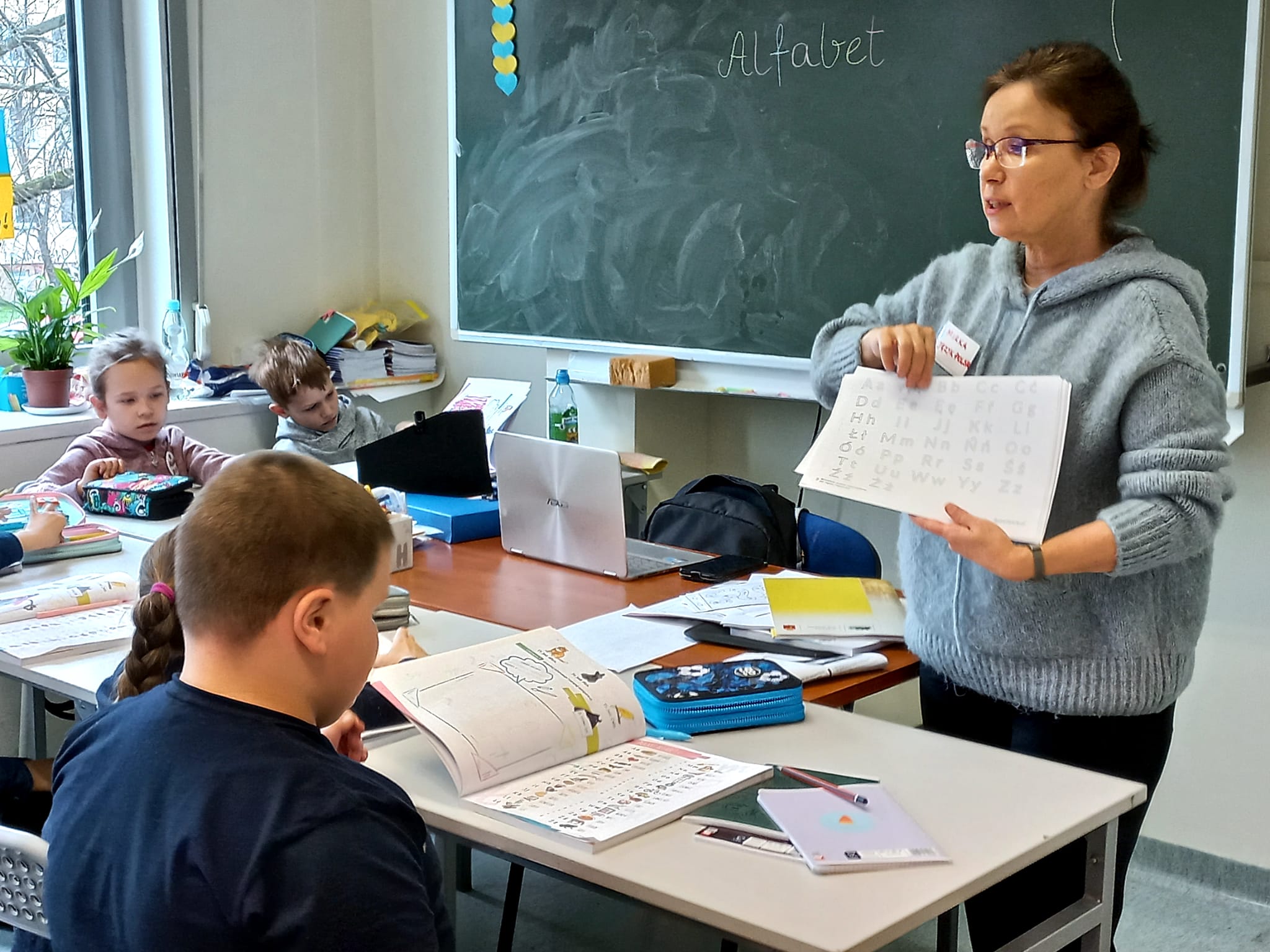 Nauczycielka pokazująca klasie kartkę z alfabetem