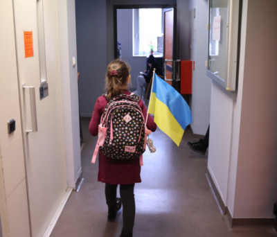 Dziewczynka z plecakiem i ukraińską flagą idąca korytarzem
